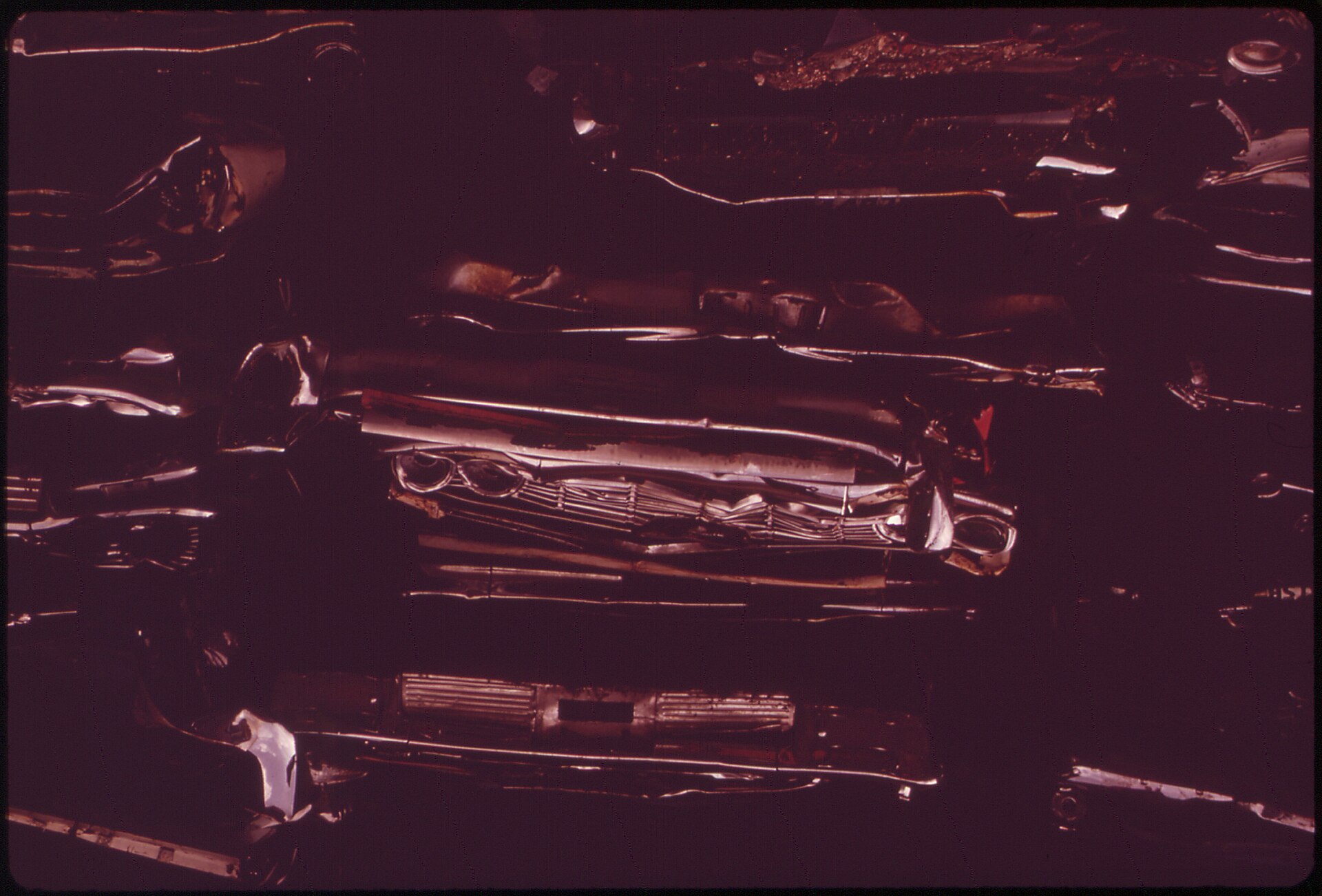 Flattened cars queued for a shredder. Whatever holds the body together goes through the hammermill with it.