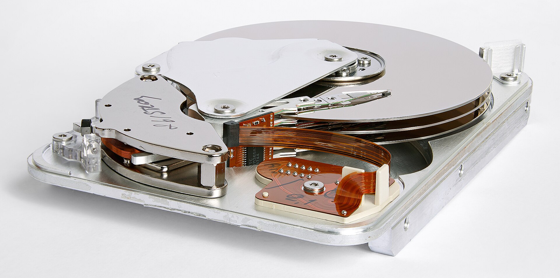 Inside a drive: the actuator magnet sits at the corner of the platter assembly, under a steel keeper plate.