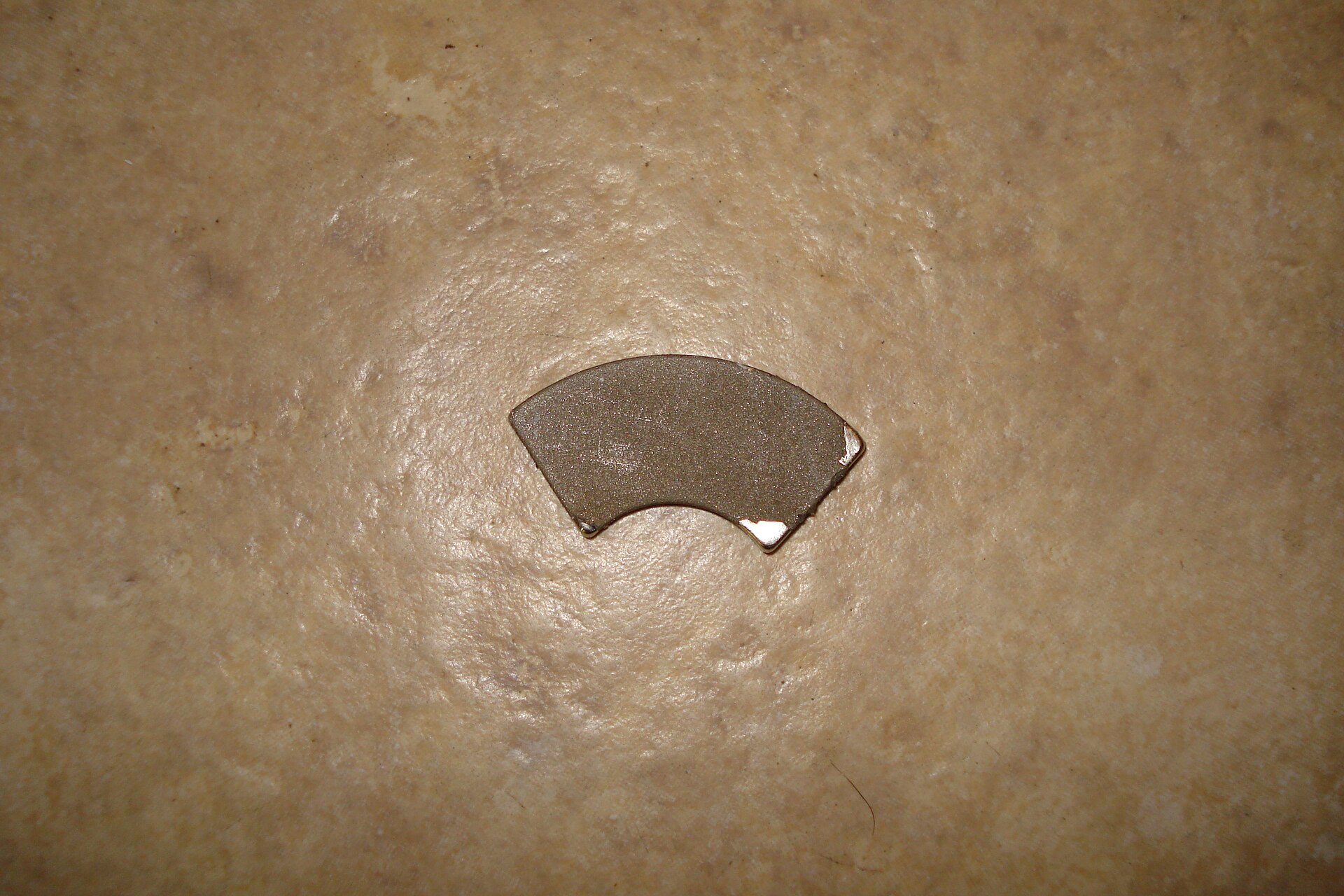 A sintered NdFeB magnet. Dense, brittle, ferociously strong, and awkward to do anything with once it is inside a device.